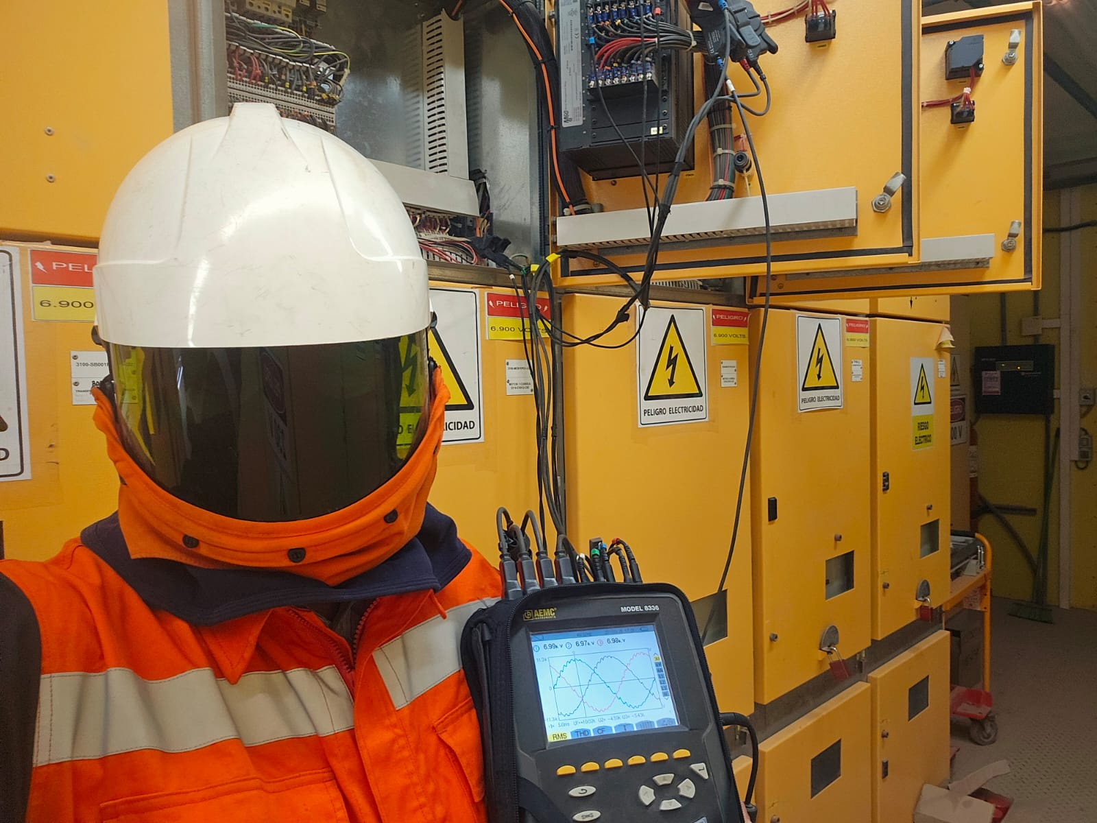 Ingeniero en terreno realizando mediciones con casco blanco y chaqueta naranja