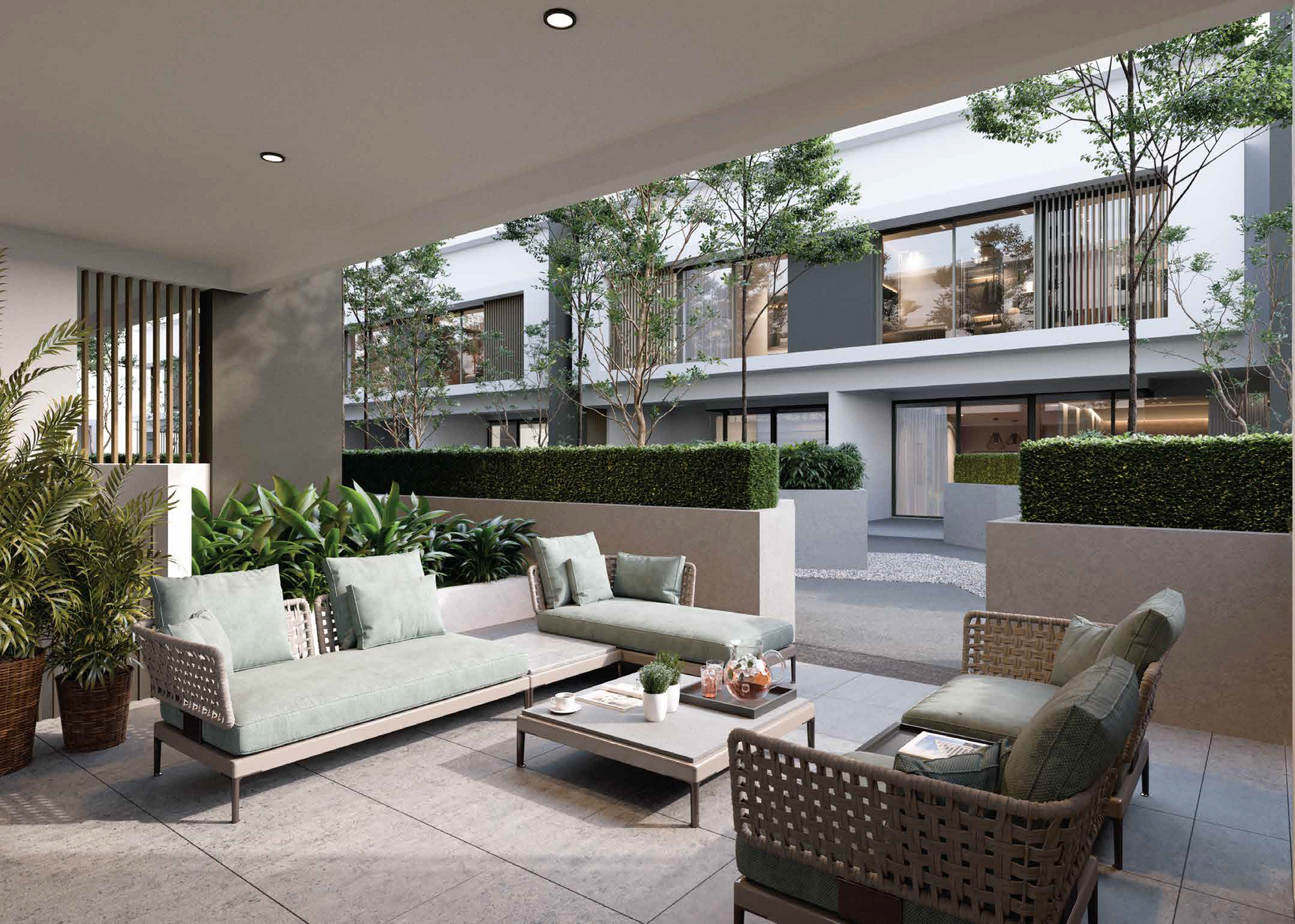 Modern outdoor patio furnished with a set of woven sofas and framed by manicured hedges